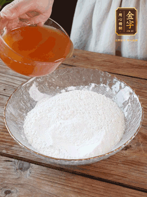 轉(zhuǎn)化糖漿、枧水、花生油攪拌均勻，加入面粉混合，醒發(fā)2小時(shí)。捏成23g一個(gè)的小球